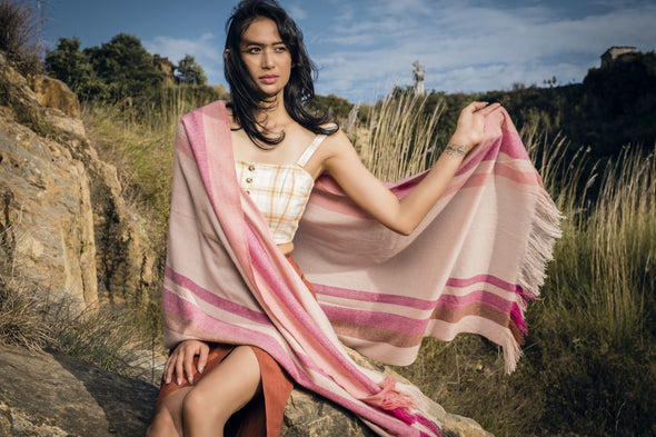 Model wearing cashmere stripe scarf in shades of cream, tan, pink, coral. Handwoven and sustainably made from eco dyes by Thread Tales